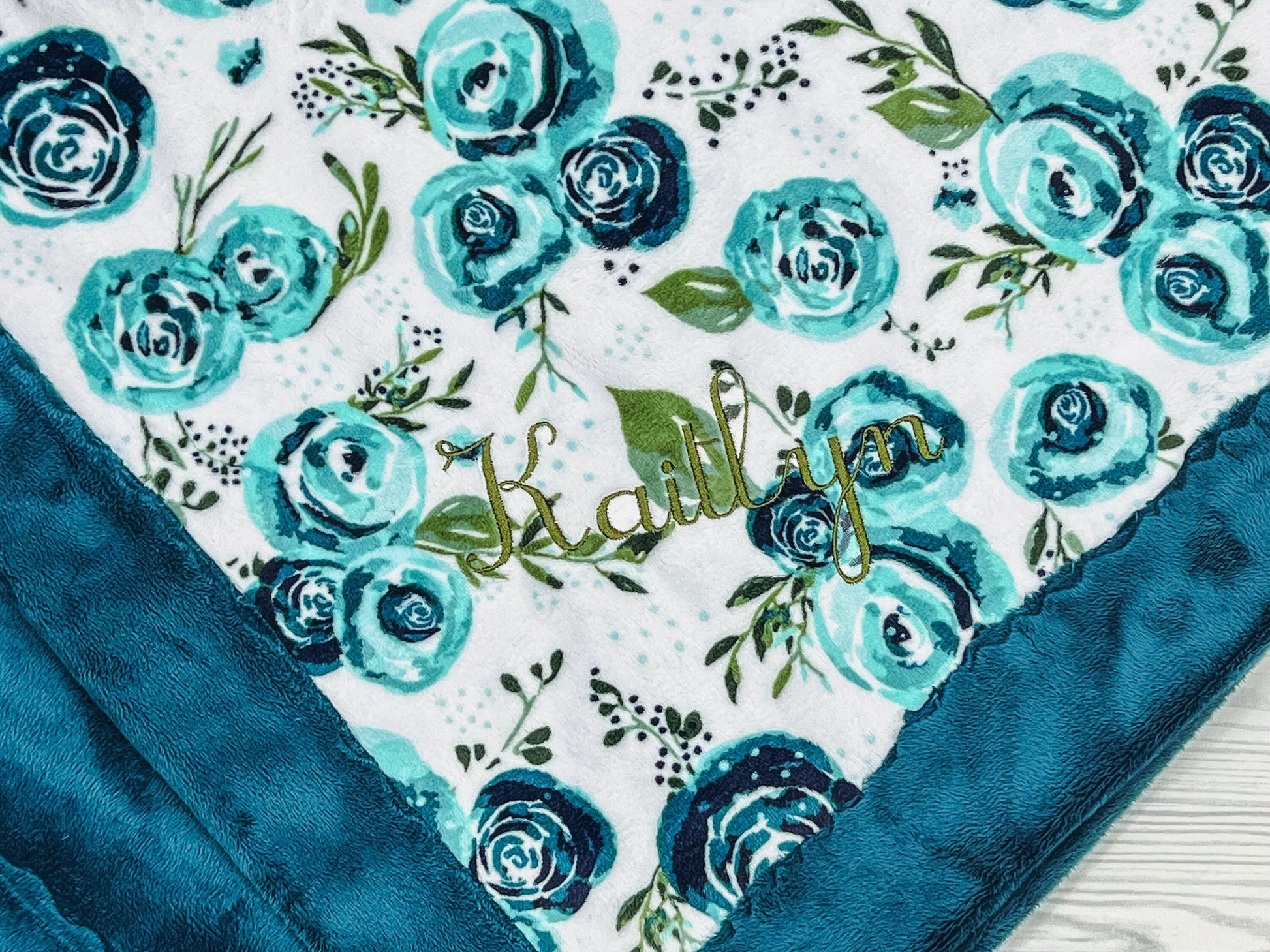 The blanket has a soft feel and can be used on both sides. The blanket front has beautiful teal flowers on the front.The back of the blanket is teal.A single embroidered name is optional.